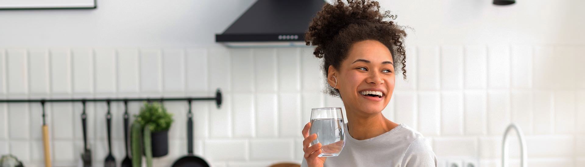 mujer feliz con un vaso de agua purificada
