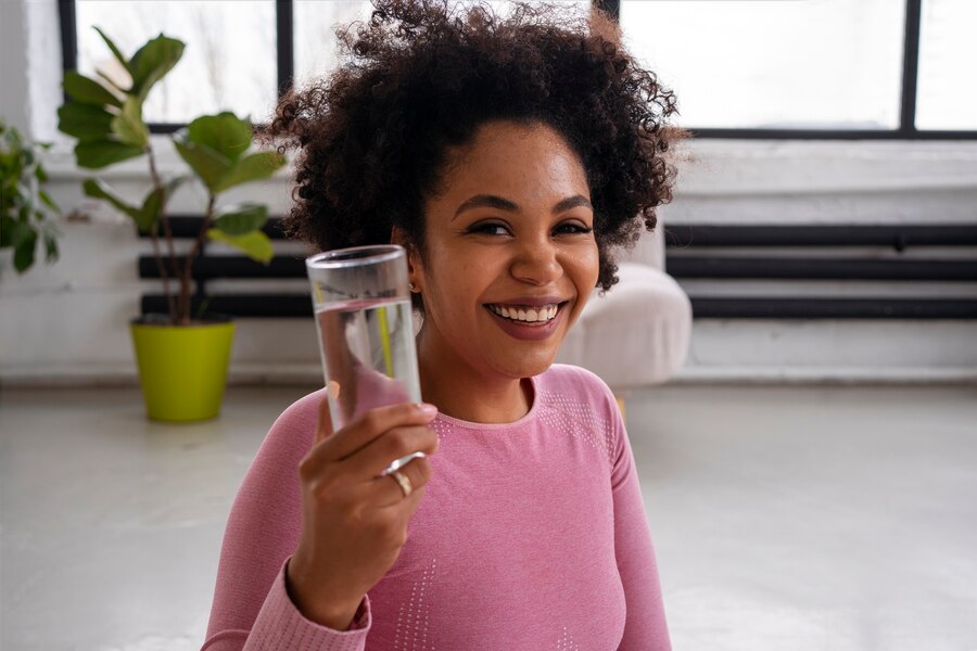 mujer tomando un vaso de agua purificada