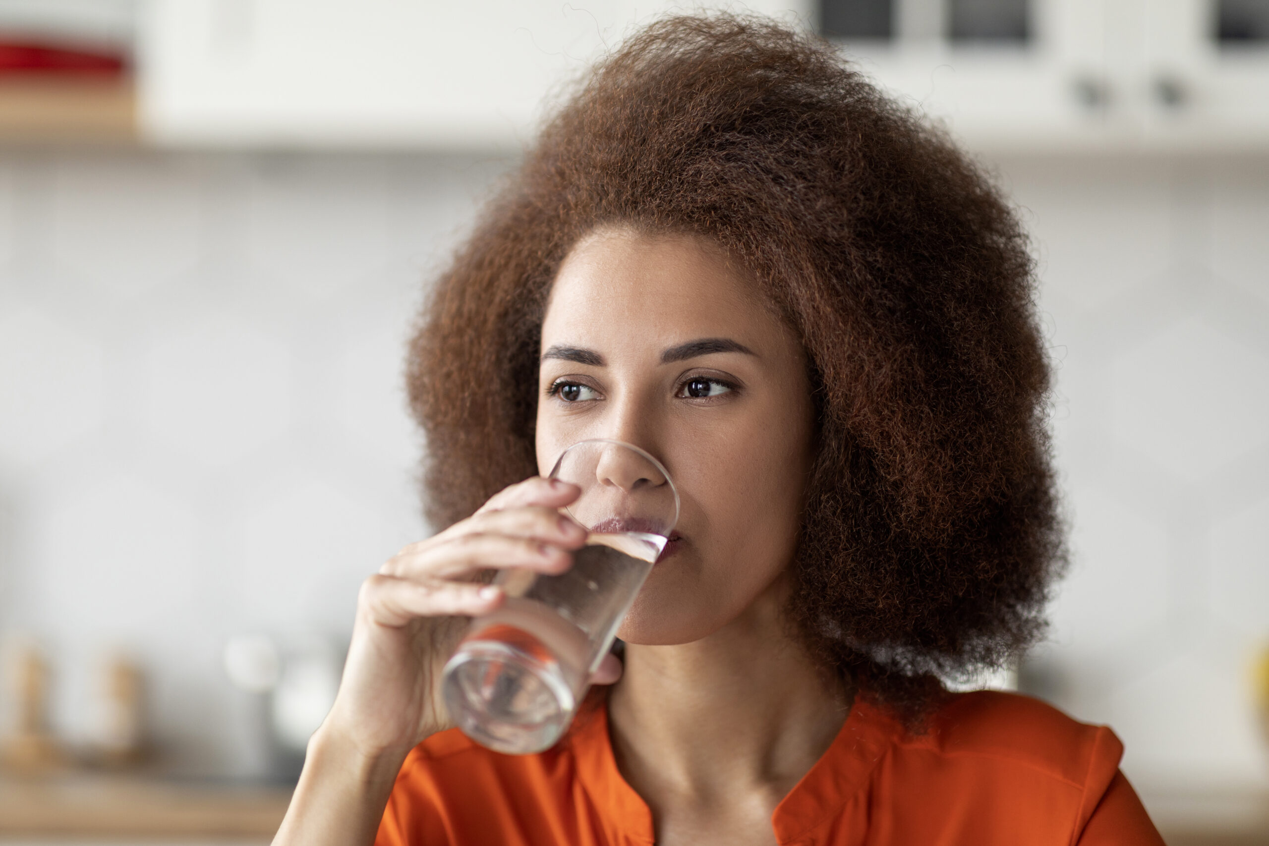 Healthy Liquid. Beautiful Black Woman Drinking Mineral Water From Glass In Kitchen